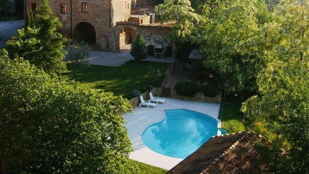 A villa with a swimming pool, surrounded by lush greenery and stone buildings. - Borgo La Grancia (Montalcino)