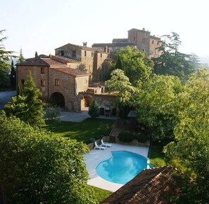 A villa with a swimming pool, surrounded by lush greenery and stone buildings. - Borgo La Grancia (Montalcino)