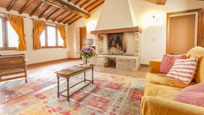A cozy living room with a fireplace, a sofa, a coffee table, and a patterned rug. - Borgo La Grancia (Montalcino)