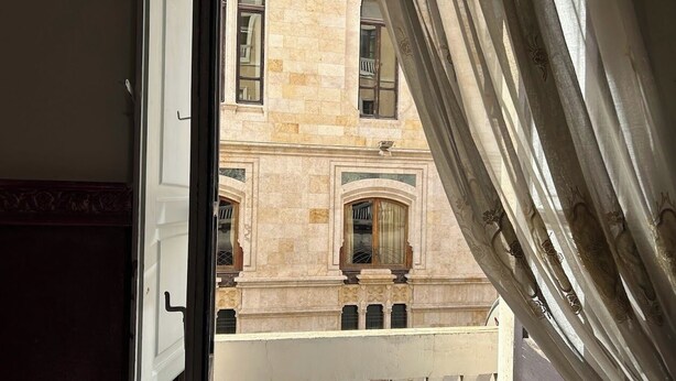 A view through an open door with a balcony, featuring a building with stone facade and arched windows. - Le Tre Stelle (Cagliari)
