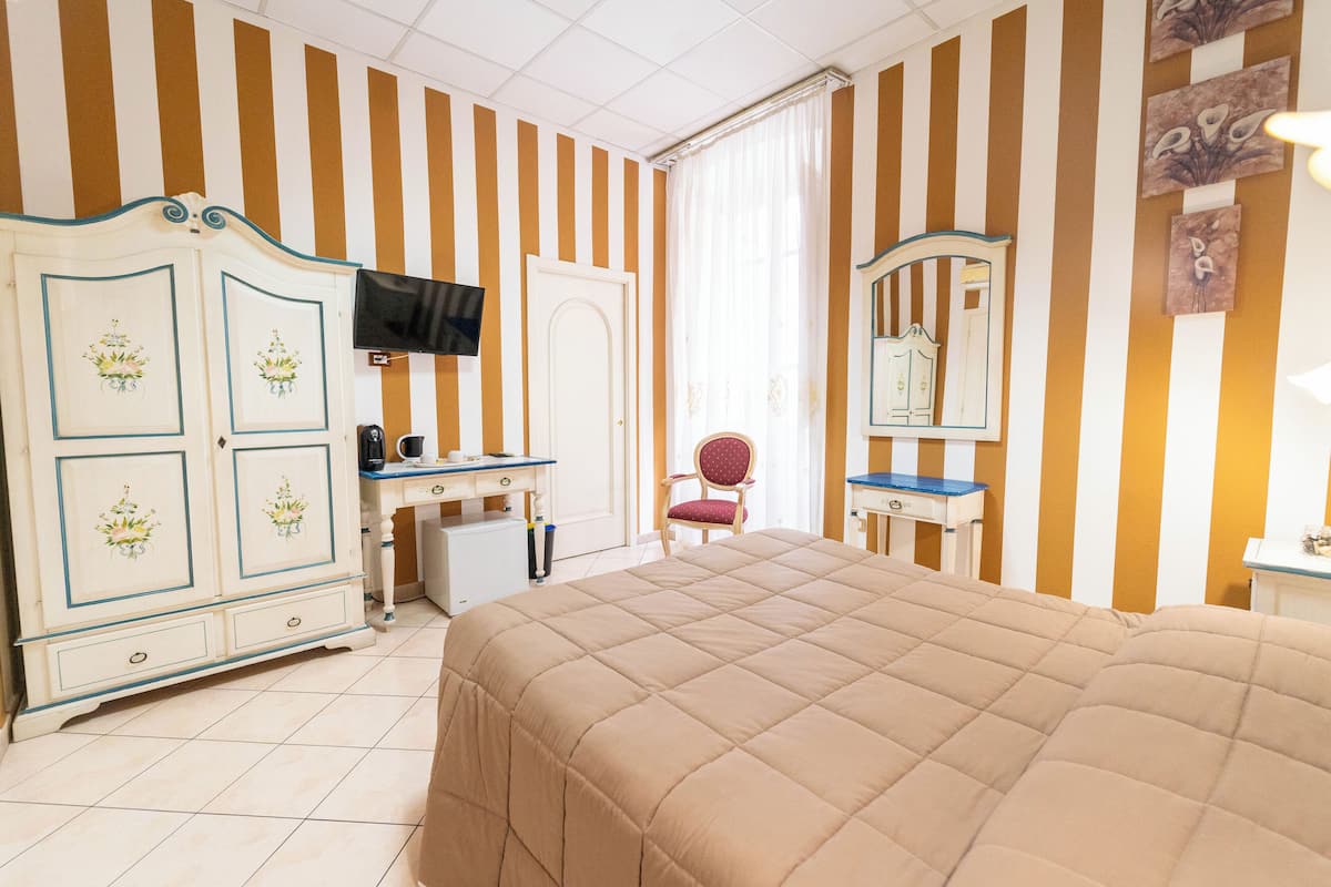 Ein Hotelzimmer mit Bett, Schreibtisch, Sessel, Fernseher und Kleiderschrank.