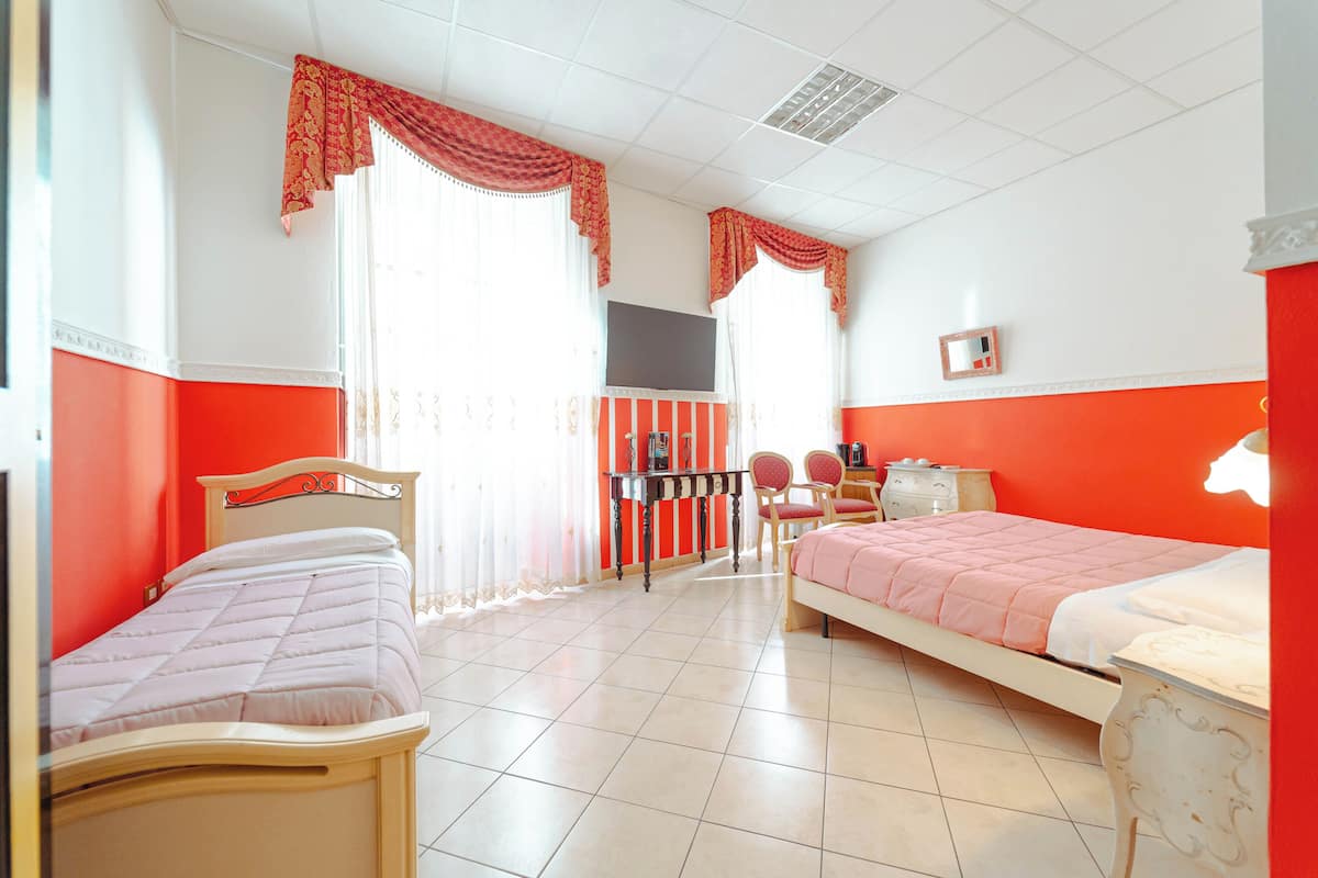 Ein Zimmer mit zwei Betten, einem Schreibtisch, Stühlen und einem Fernseher.