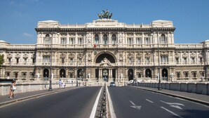 A grand building with a central entrance, large windows, and a statue on top.