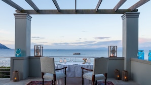 Una terraza con una mesa preparada para dos, con vista a un cuerpo de agua.