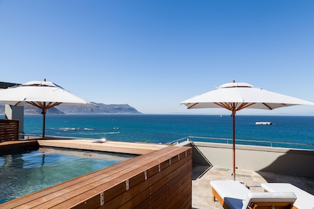 Una piscina al aire libre, sombrillas, sillones reclinables de piscina