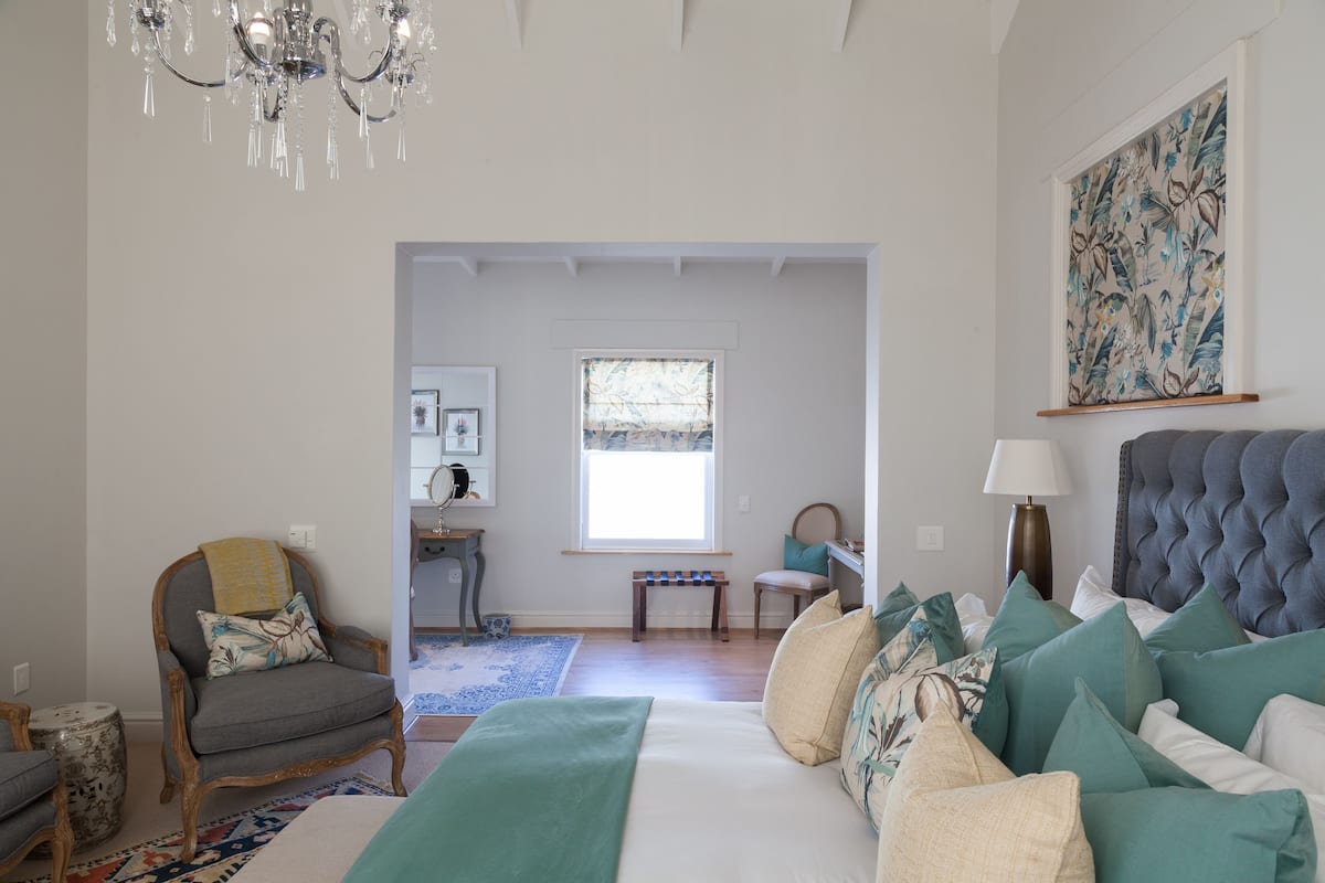 Une chambre à coucher avec un lit, une chaise, une lampe et un lustre.