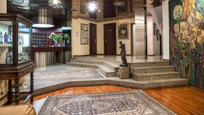 Un vestíbulo con una recepción, una estatua y un mural grande.
