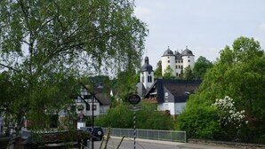 A traditional building with a tower, surrounded by lush greenery and a sign indicating a nearby establishment. - Hotel Restaurant Gemünden (Gemuenden)