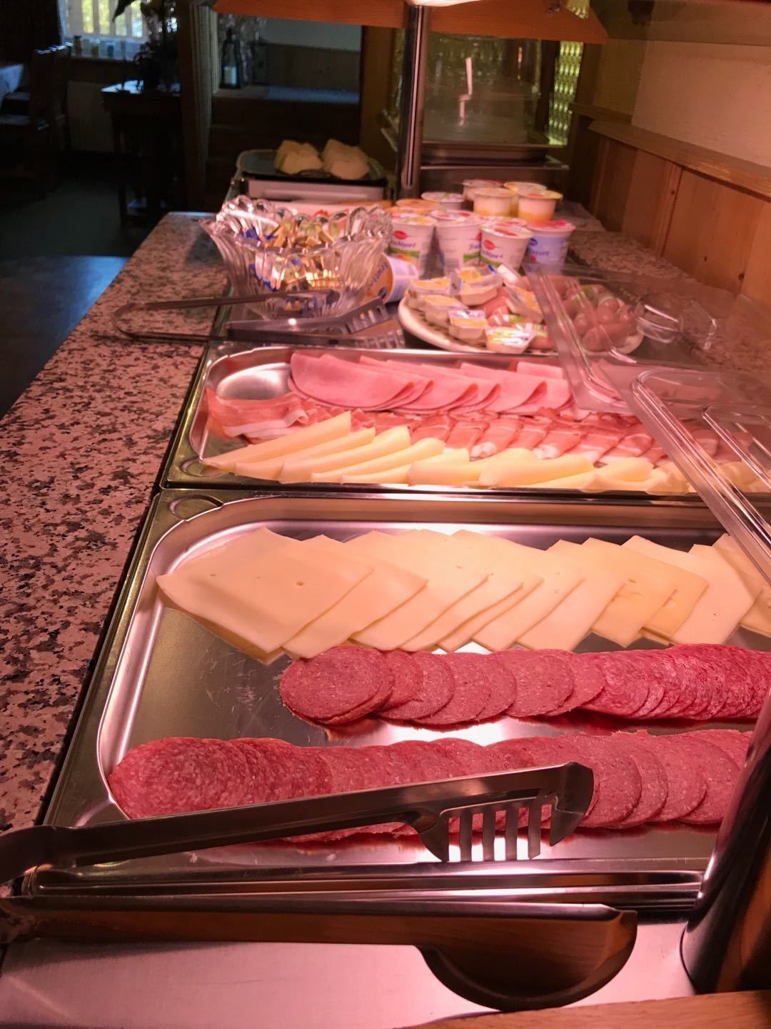 Buffetpöydässä on tarjolla monenlaista ruokaa, kuten viipaloituja lihatuotteita, juustoja ja muita valmiita ruokia.