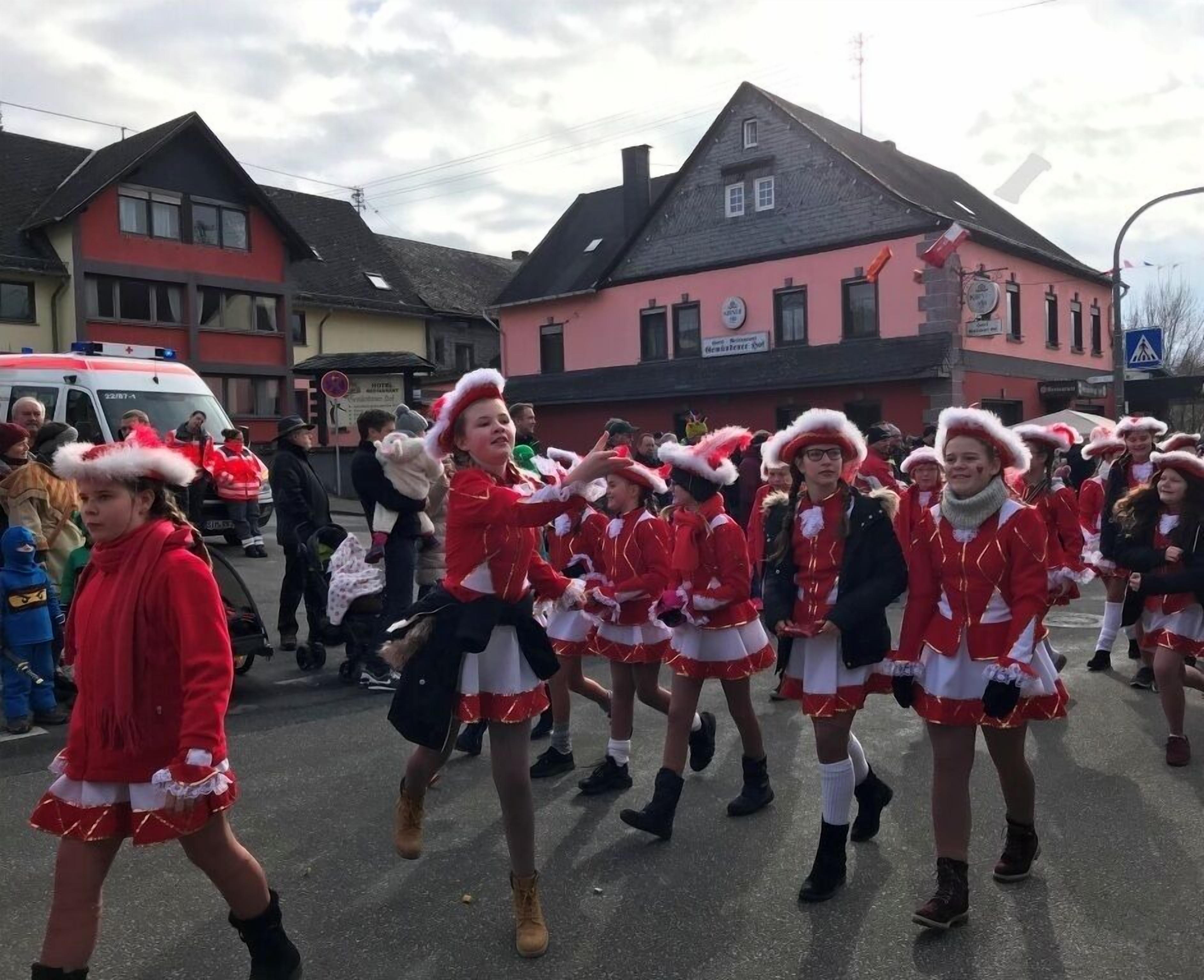 Un grupo de personas con atuendo festivo caminando por una calle.