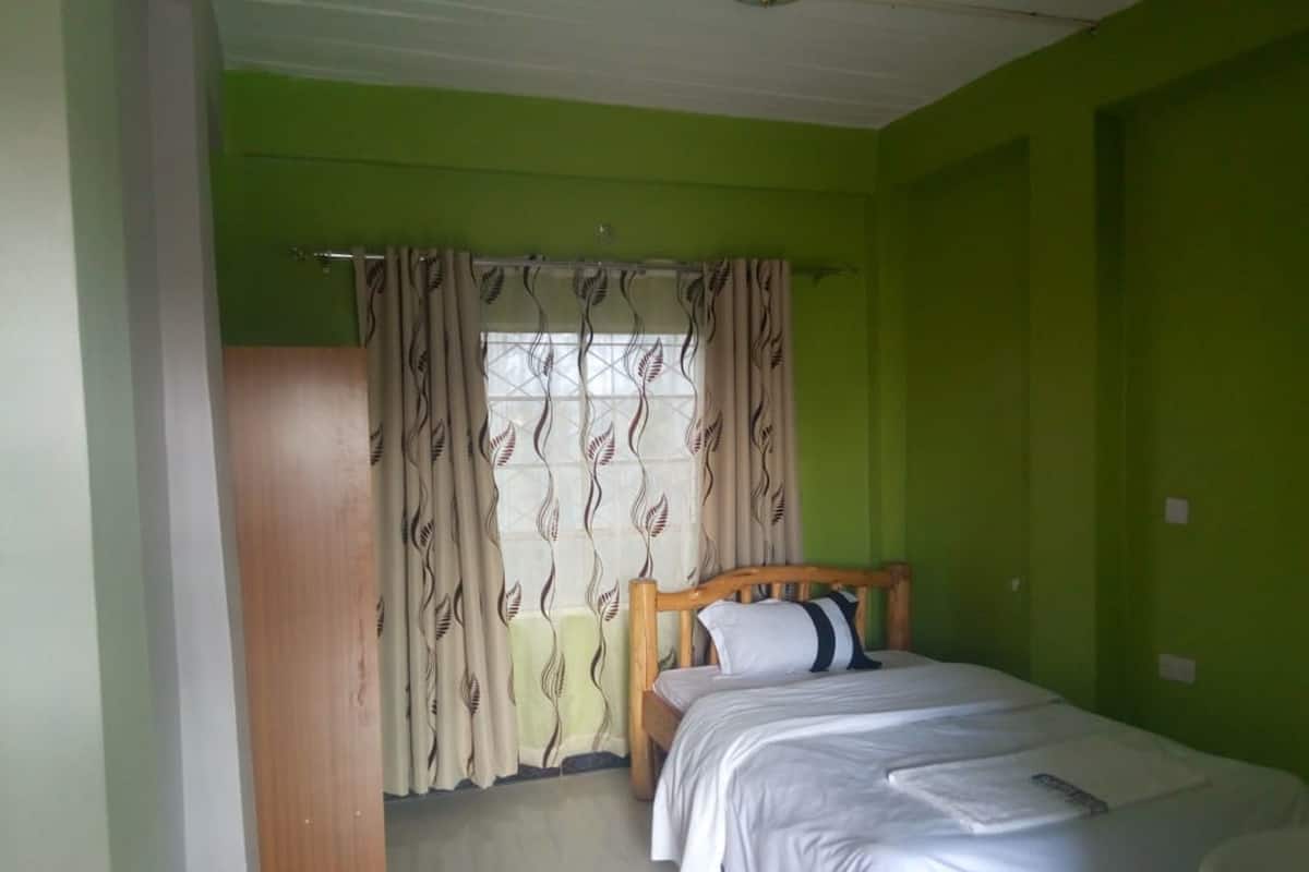 A bedroom with a bed, a wardrobe, and a window with curtains.
