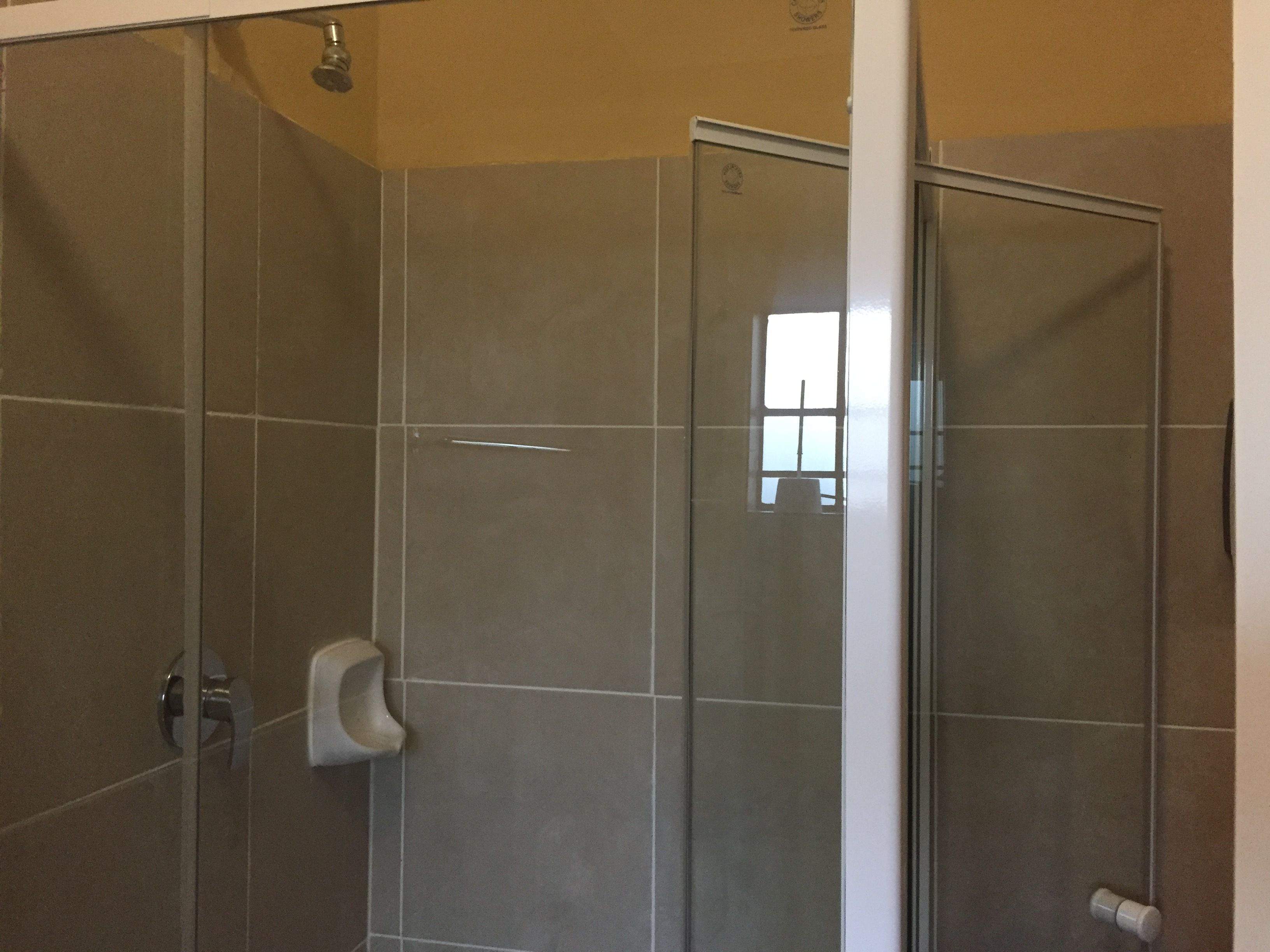A glass-enclosed shower with a hand dryer and a visible window.