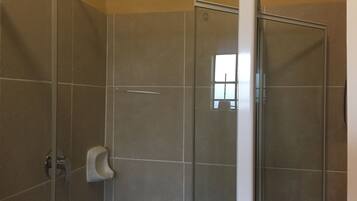 A glass-enclosed shower with a hand dryer and a visible window.
