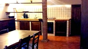 A compact living space with a dining area, kitchenette, and a blue sofa with a patterned pillow. - Agriturismo San Filippo (Acquapendente)