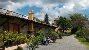 A courtyard with a gravel path, potted plants, and outdoor seating. - Agriturismo San Filippo (Acquapendente)