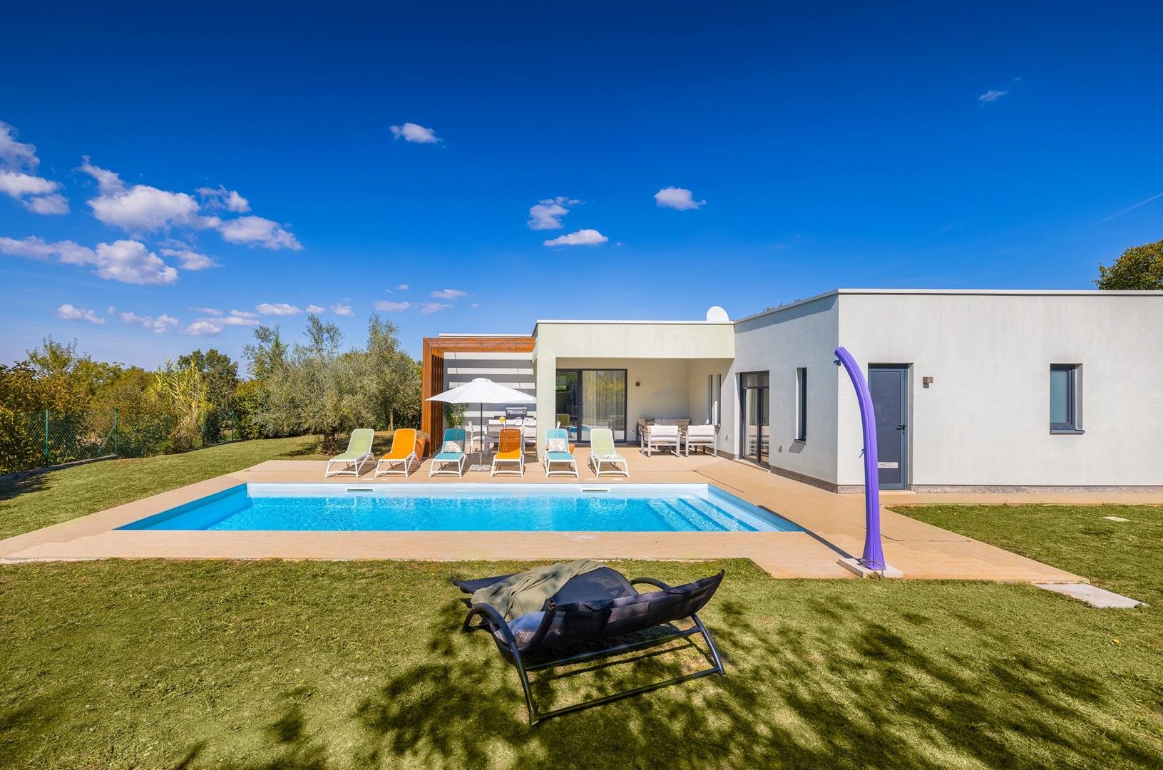 A modern house with a swimming pool, outdoor seating, and a covered patio.