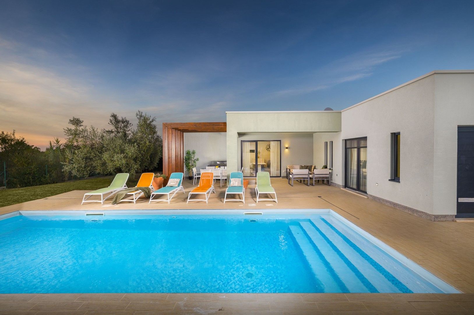 A modern house with a swimming pool, outdoor seating, and a patio area.