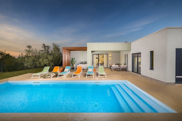 Una casa moderna con piscina, mobiliario exterior y zona de patio.