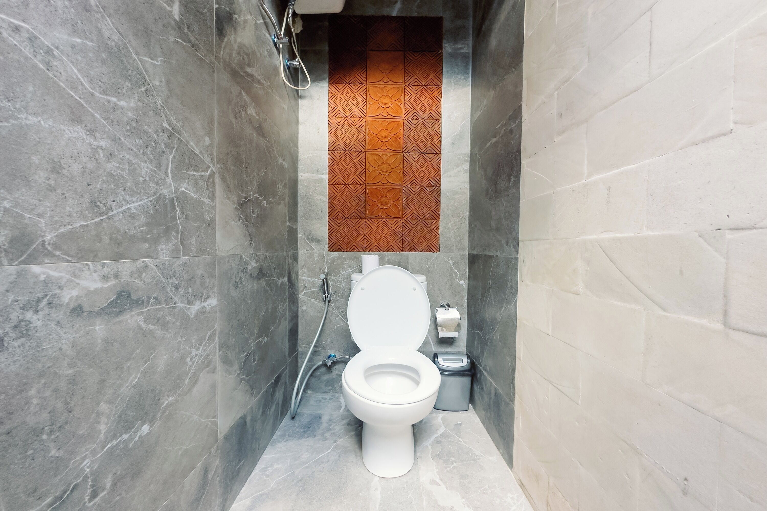 A modern bathroom with a white toilet, a shower, and a wall-mounted towel rack.