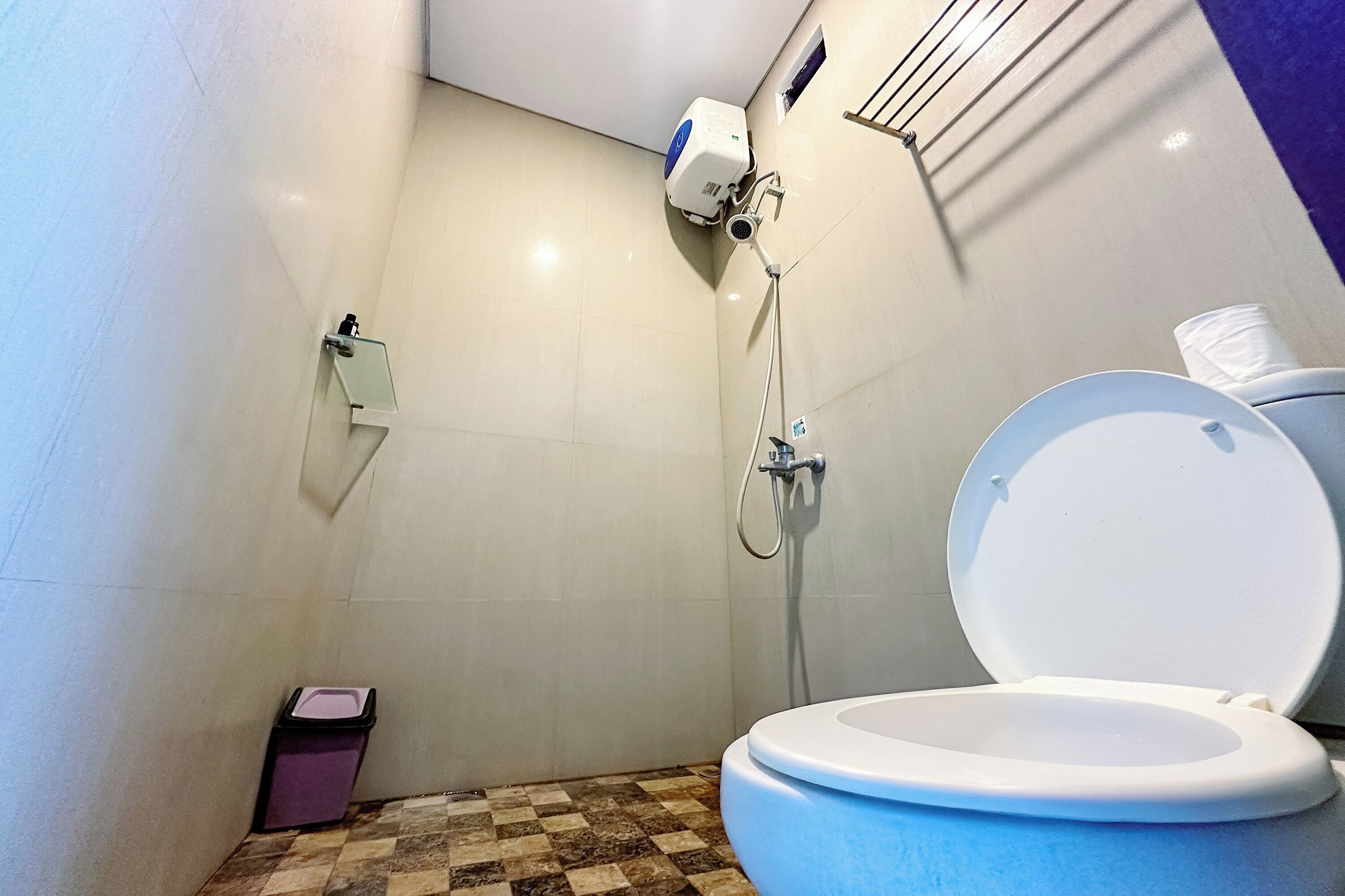 Een badkamer met toilet, douche en een prullenbak.