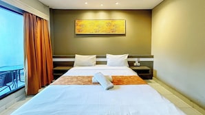Una camera d'albergo con un letto grande, una finestra con tende, un quadro appeso al muro e un balcone.