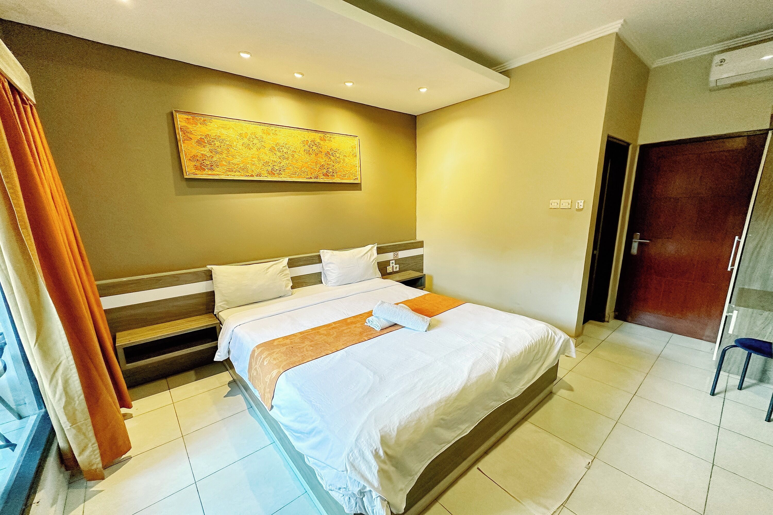 Een hotelkamer met een bed, een schilderij aan de muur en een deur.