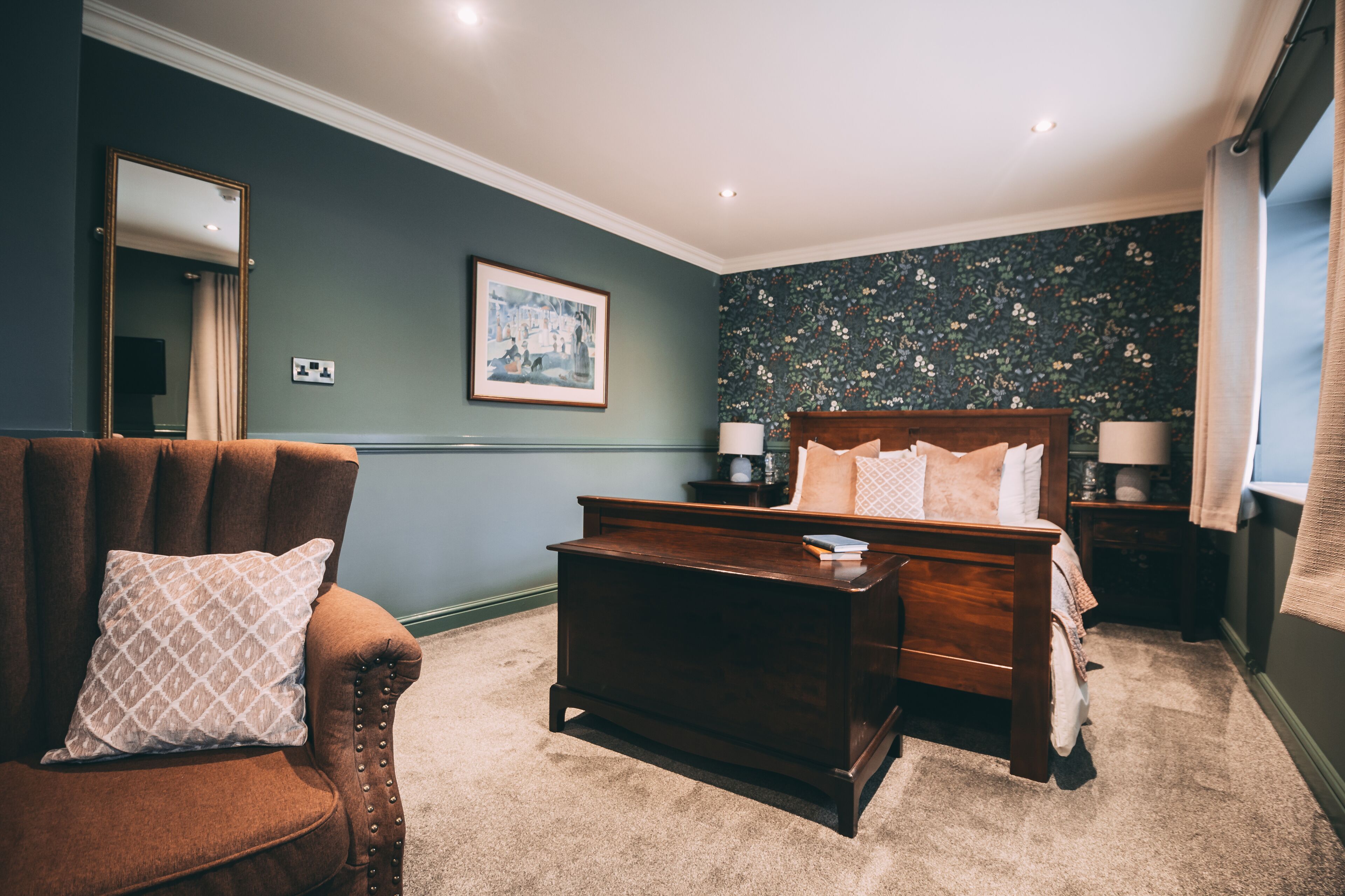 A bedroom with a bed, a chair, a nightstand, and a dresser.