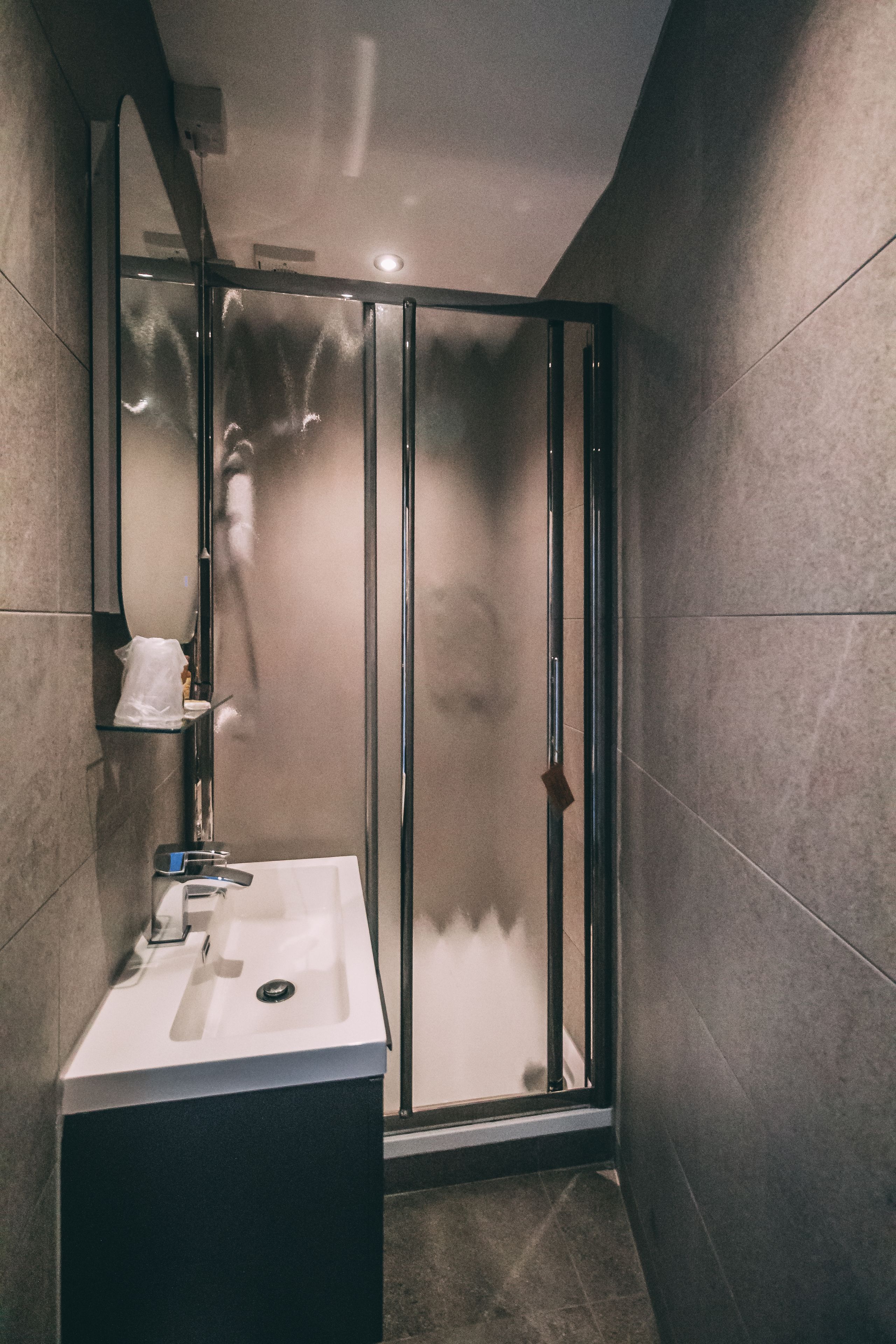 A modern bathroom with a glass-enclosed shower, a white sink, and a mirror.