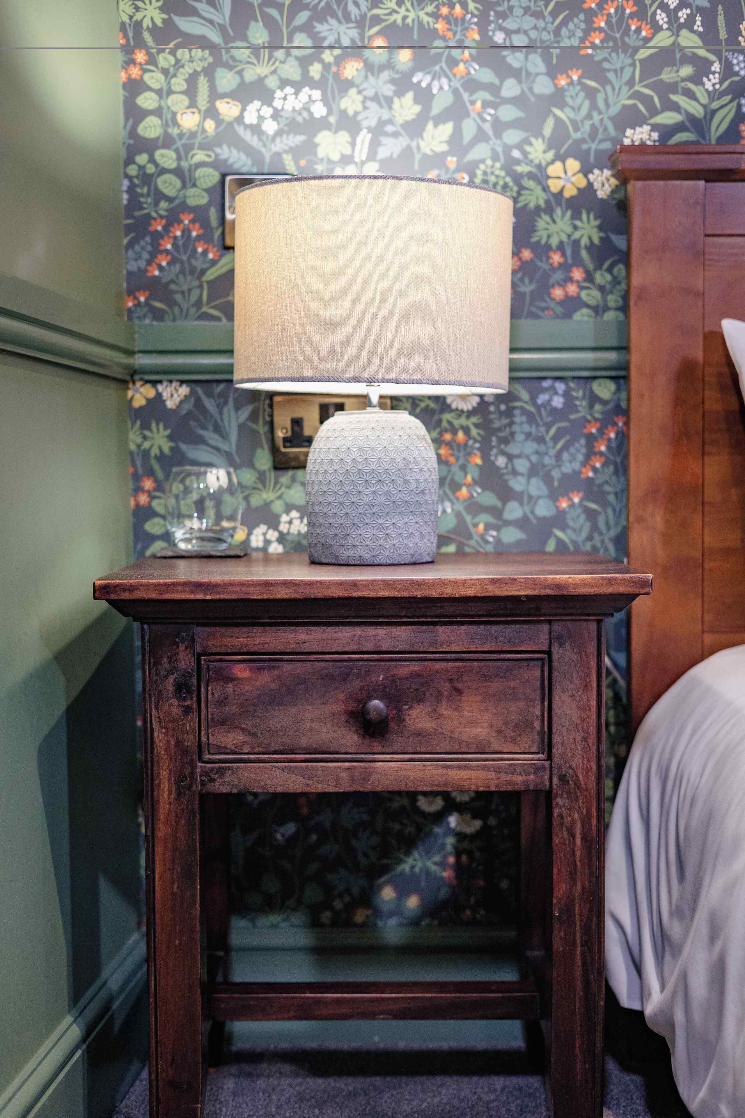 A wooden nightstand with a lamp and a decorative item.