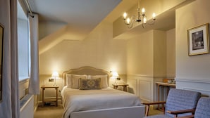 Un dormitorio con una cama grande, dos mesitas de noche con lámparas, una silla y un candelabro.