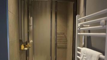 Un baño moderno con ducha de vidrio, lavamanos blanco y barra para toallas.