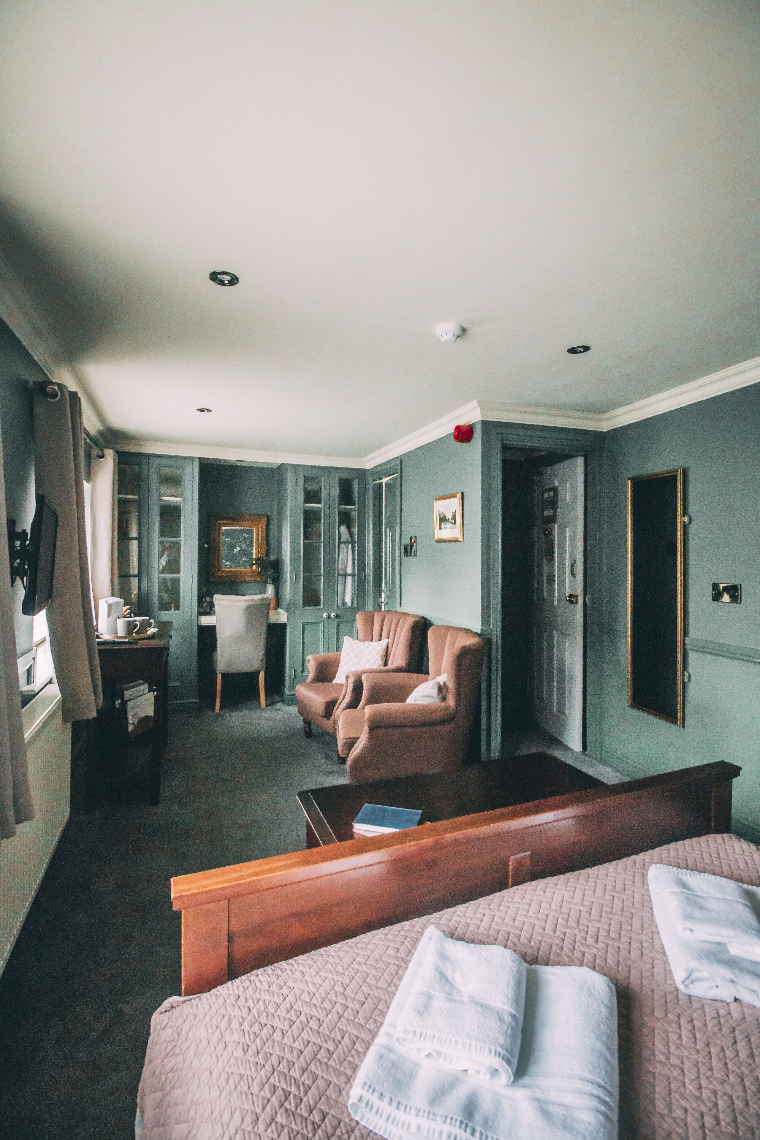 A hotel room with a bed, a desk, a chair, and a wardrobe.