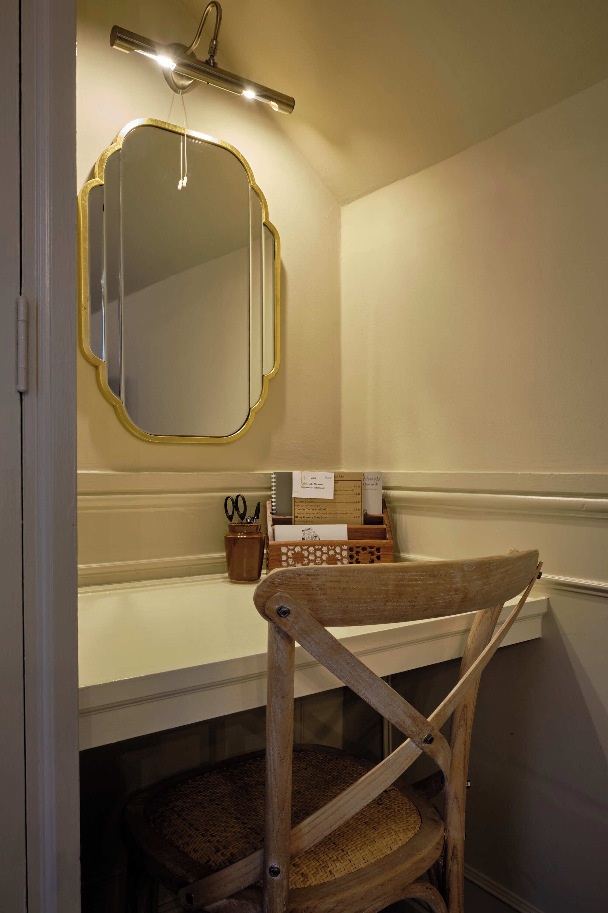 Un bagno con uno specchio, un portasciugamani e una sedia di legno.