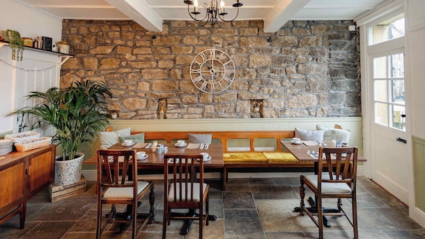 Un comedor acogedor con pared de piedra, mobiliario de madera y un reloj grande.
