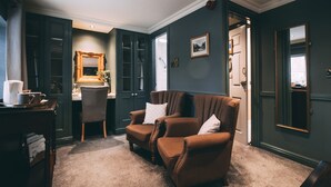 Una habitación con dos sillones marrones, un escritorio con espejo y una estantería.