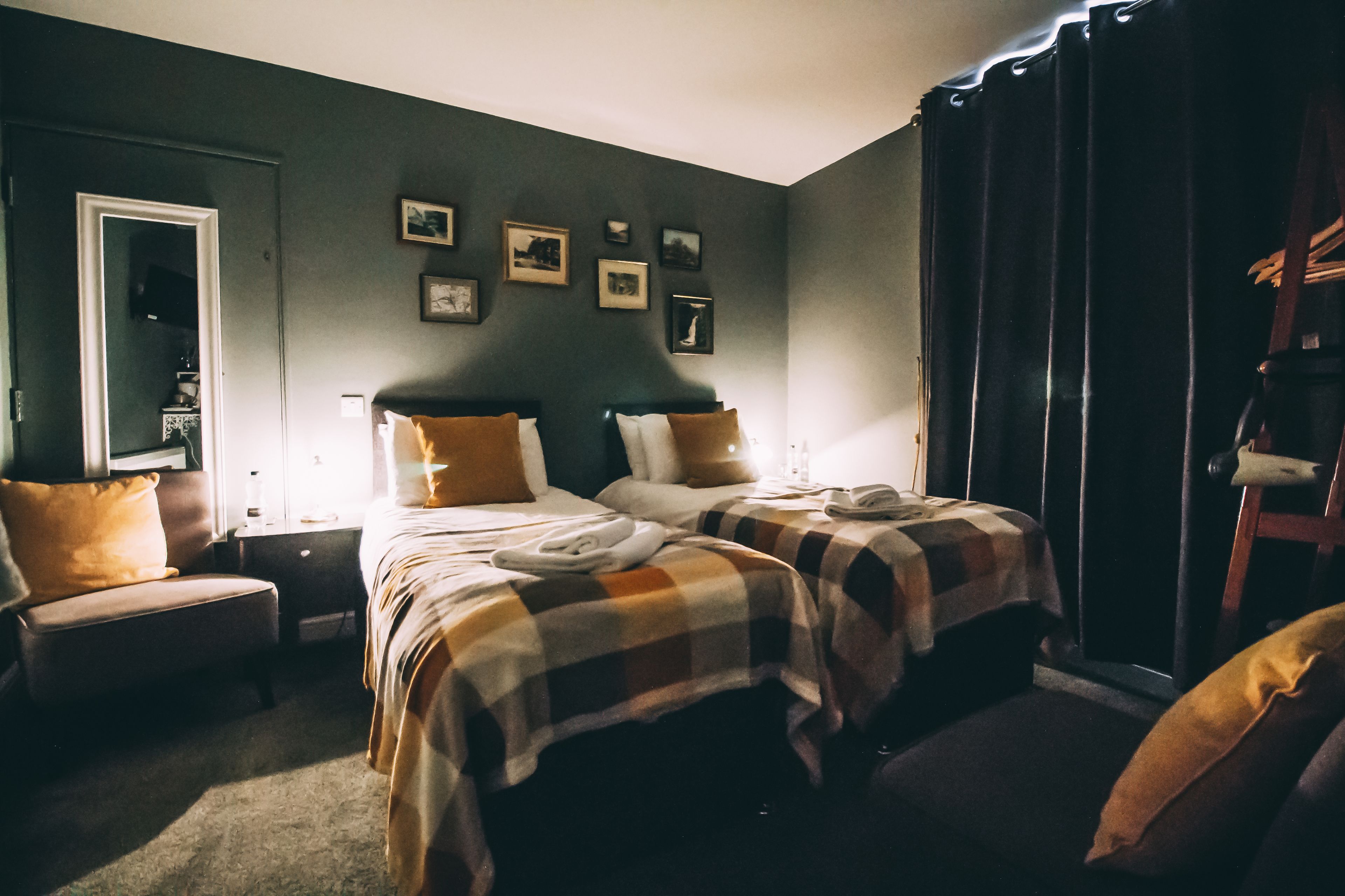 A bedroom with two beds, a nightstand, a chair, and a wardrobe.