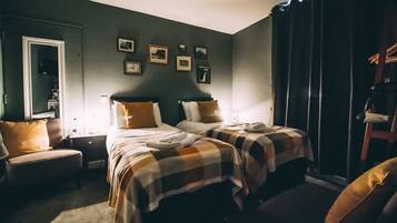 A bedroom with two beds, a nightstand, a chair, and a wardrobe.