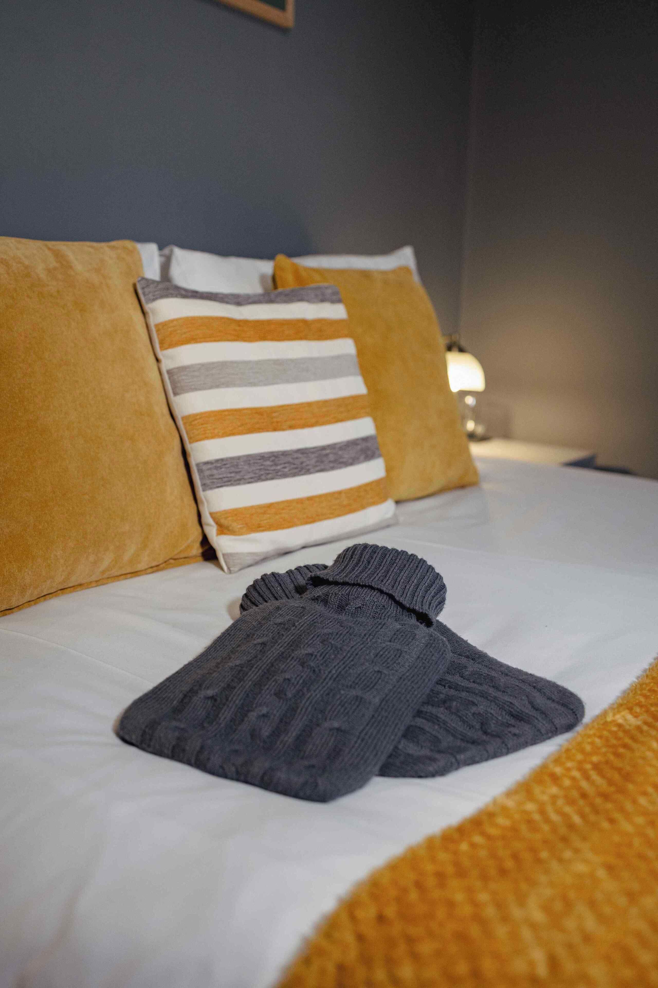 Una cama bien hecha con sábanas blancas, una almohada a rayas y un par de calcetines grises.