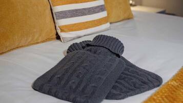 Una cama bien hecha con sábanas blancas, una almohada a rayas y un par de calcetines grises.
