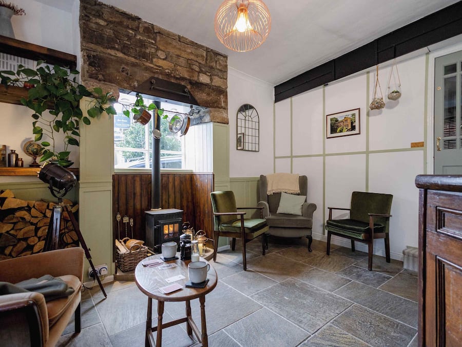 A cozy living room with a fireplace, comfortable seating, and a rustic stone wall.