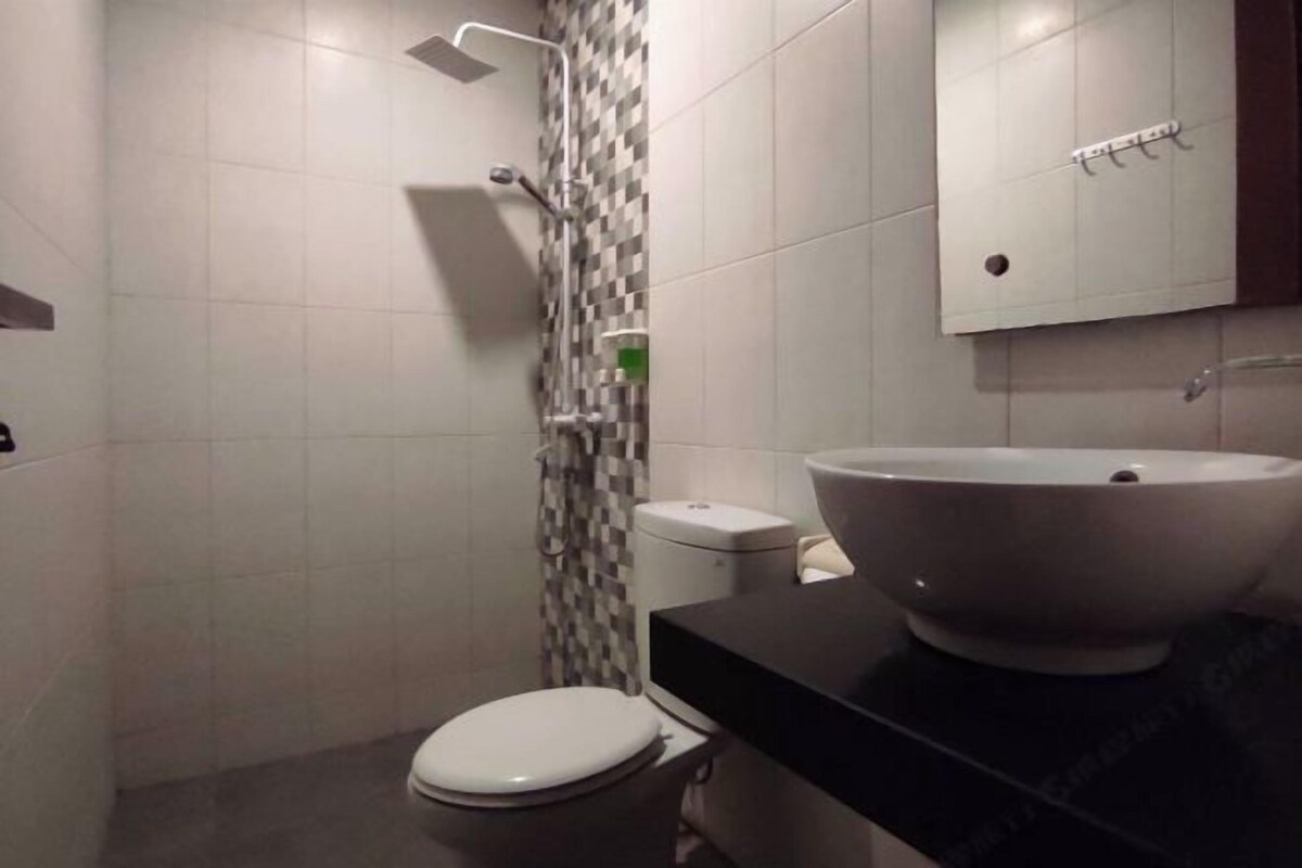 A bathroom with a white toilet, a shower, and a sink with a large basin.