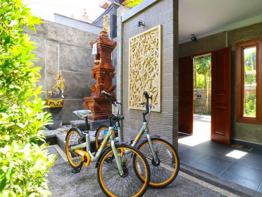A courtyard with a bicycle, a decorative pillar, and a door leading to a room.