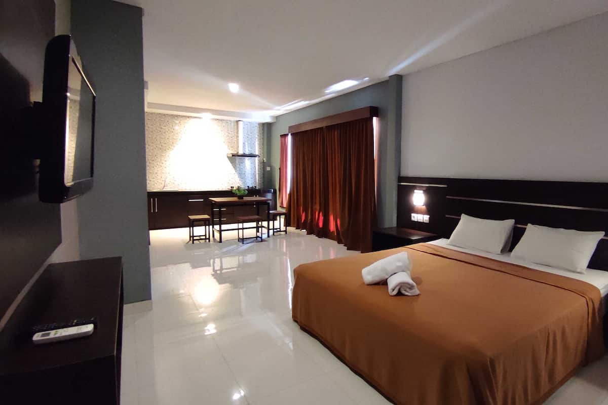 A hotel room with a large bed, a desk, and a chair.