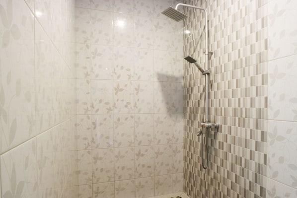 Un espacio de ducha con pared de azulejos y ducha.