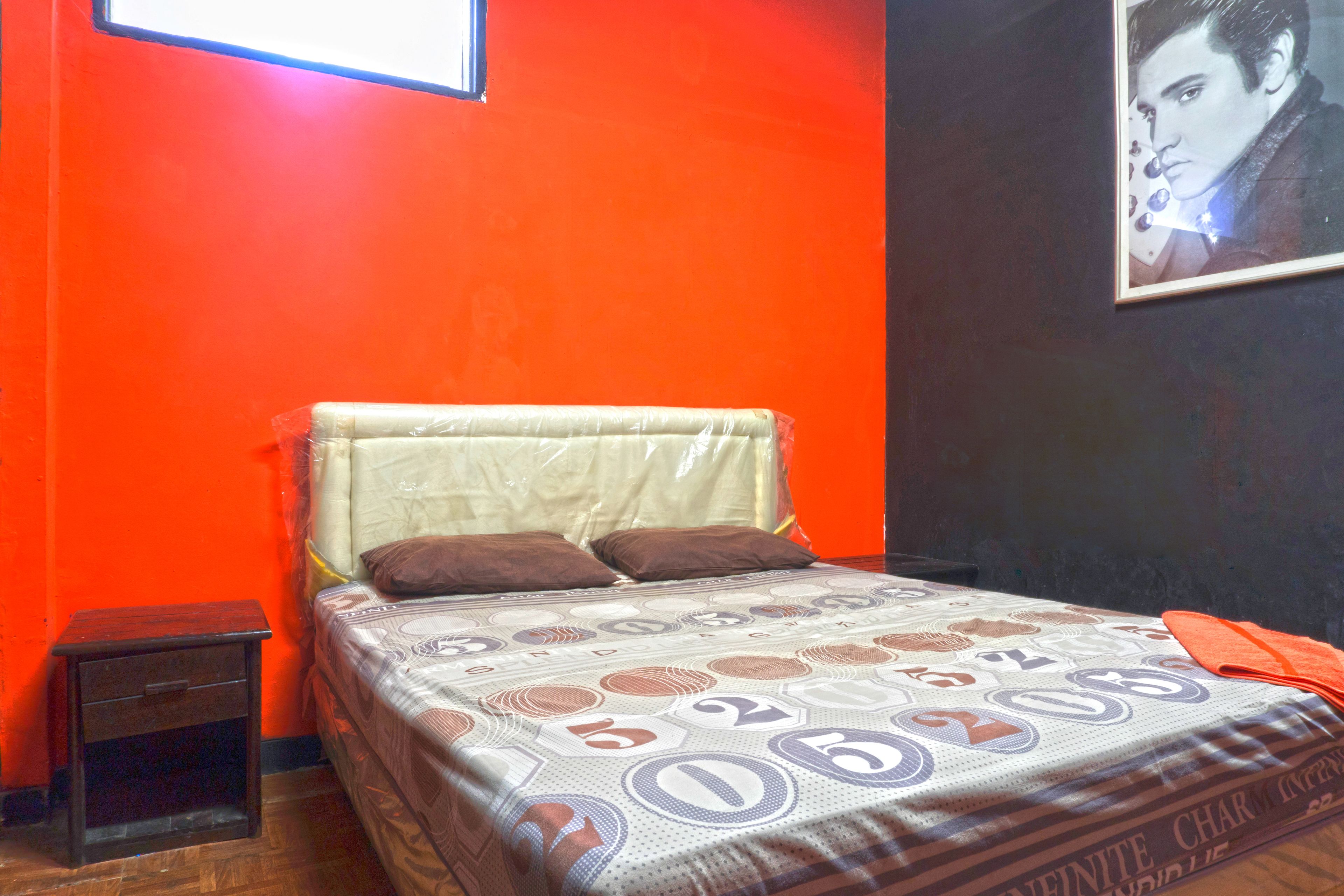 A bed with a patterned bedspread, a nightstand, and a framed picture on the wall.