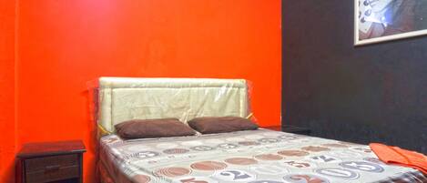 A bed with a patterned bedspread, a nightstand, and a framed picture on the wall.