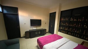 A bedroom with two beds, a TV, a bookshelf, and a door. - Wisma Tobana (Jakarta)