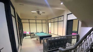 A hallway with a pool table, a staircase, and a ceiling fan. - Wisma Tobana (Jakarta)