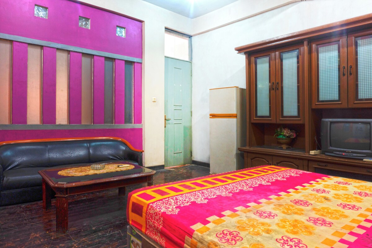 A room with a bed, a sofa, a television, and a cabinet.