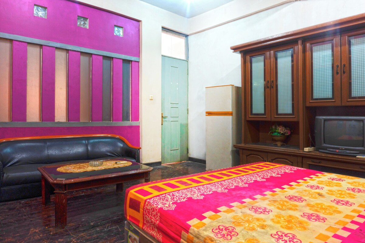 Um quarto com cama, sofá, televisão e um armário.